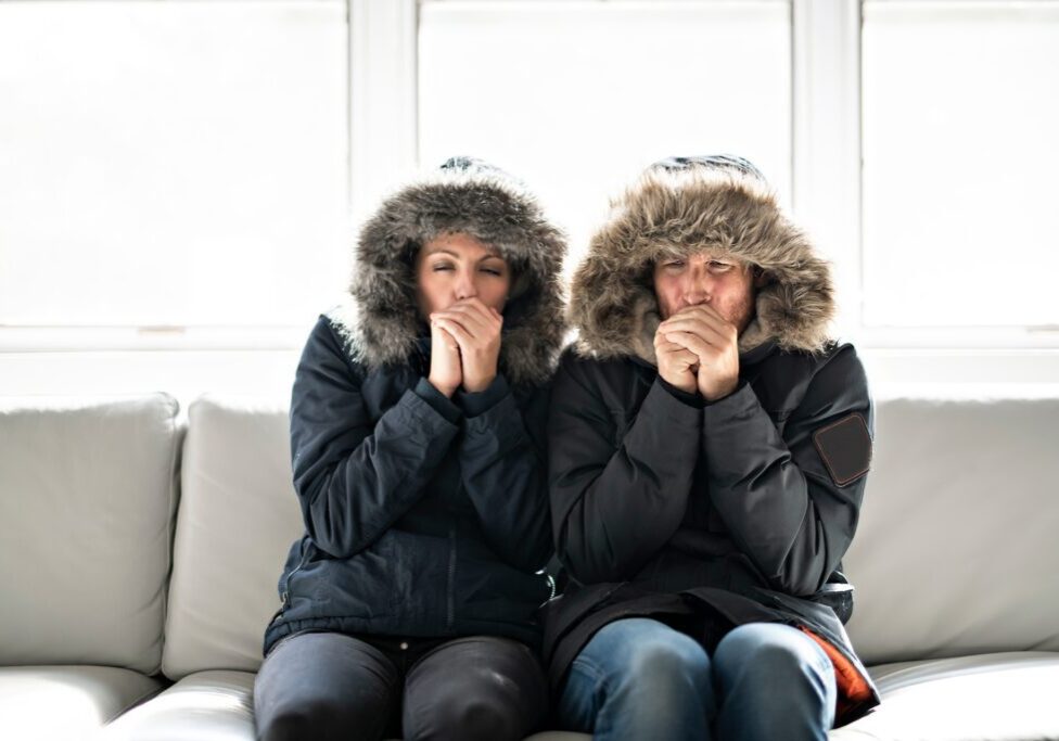 A couple wearing parkas inside of a cold house
